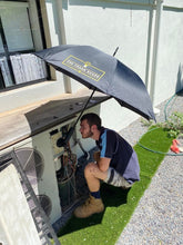Load image into Gallery viewer, Outdoor Worker Using The Trade Shade - Magnetic Umbrella Holder For Sun Protection While He Diagnosing A Faulty Air-Con.