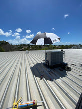 Load image into Gallery viewer, The Trade Shade - Magnetic Umbrella Holder Being Used To Provide A Large Area Of Shade While Working On A  Rooftop Air-Con.
