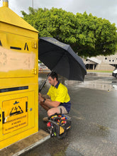 Load image into Gallery viewer, The Trade Shade - Magnetic Umbrella Holder Keeping An Australia Outdoor Worker Dry While He Works On Electrician Equipment.
